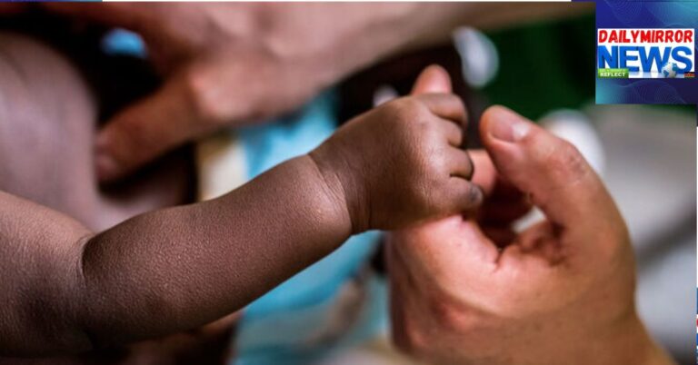 A newborn baby grips a mother's hand